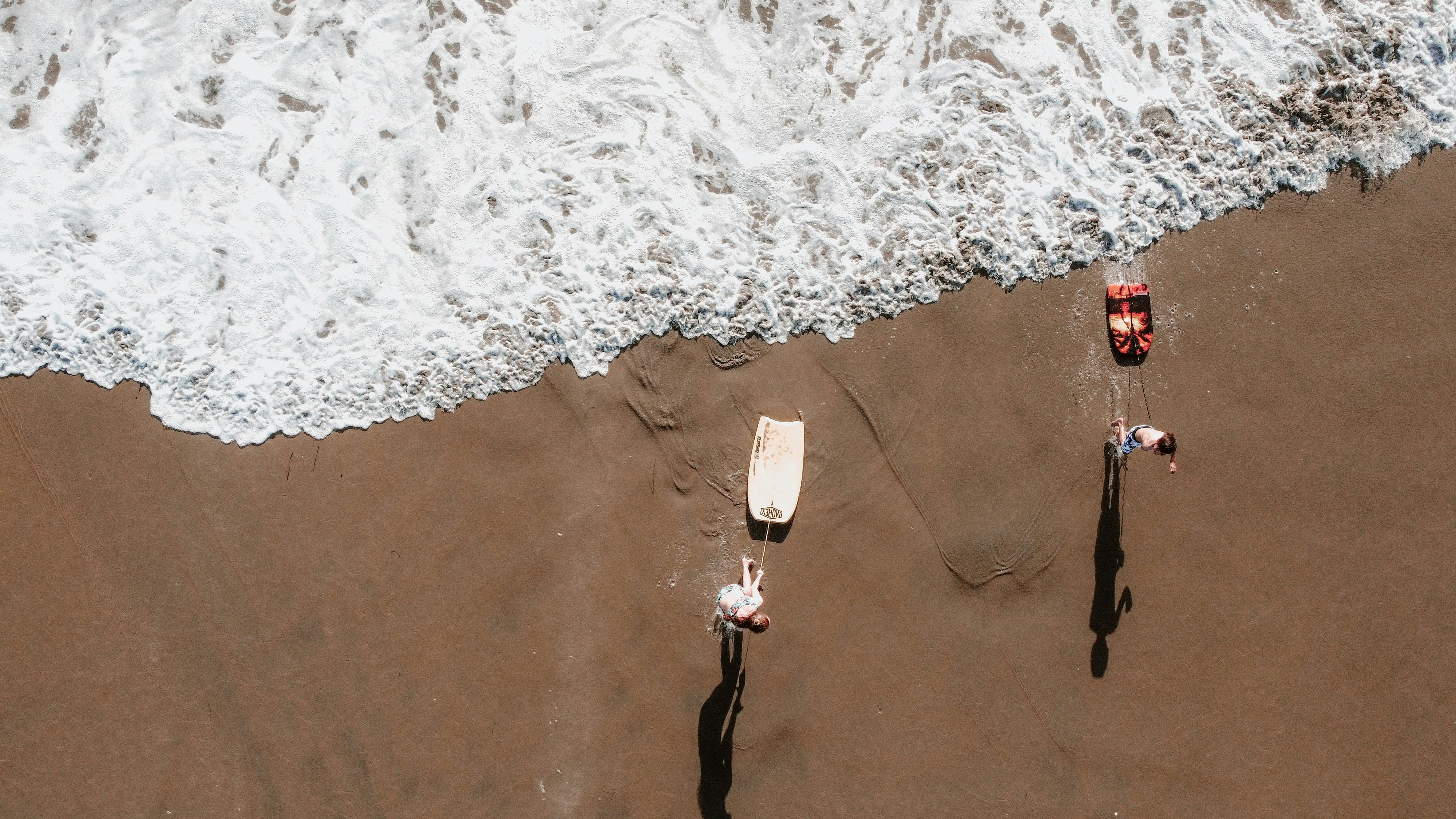 photo of 2 people going out of water with boogies